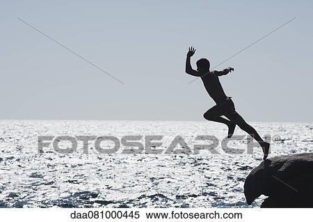 Teenage boy jumping into ocean, silhouette View Large Photo Image Stock Photography - Teenage boy jumping into ocean, silhouette. Fotosearch