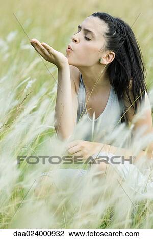 Teenage girl crouching in tall grass with eyes closed, blowing seedling View Large Photo Image Stock Image - Teenage girl crouching in tall grass with eyes closed, blowing seedling. Fotosearch