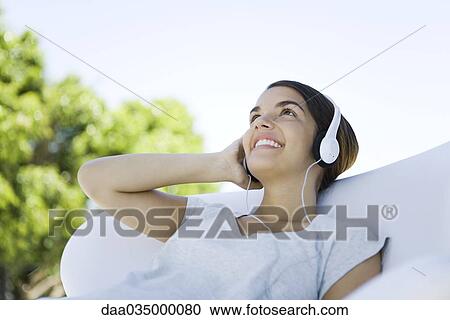 Teenage girl listening to headphones, looking up, smiling View Large Photo Image Stock Image - Teenage girl listening to headphones, looking up, smiling. Fotosearch