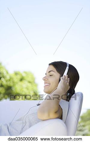 Teenage girl listening to headphones, reclining in armchair, eyes closed View Large Photo Image Stock Photography - Teenage girl listening to headphones, reclining in armchair, eyes closed. Fotosearch