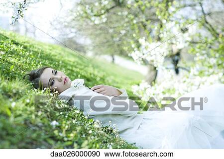 Teenage girl lying on the ground, holding flower, eyes half-opened View Large Photo Image Stock Image - Teenage girl lying on the ground, holding flower, eyes half-opened. Fotosearch