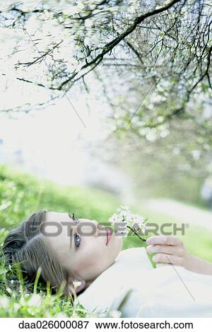 Teenage girl lying on the ground, smelling flower, looking up View Large Photo Image Stock Photo - Teenage girl lying on the ground, smelling flower, looking up. Fotosearch