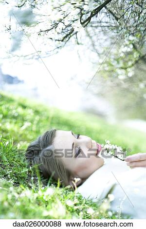 Teenage girl lying on the ground, smelling flower, eyes closed View Large Photo Image Stock Photo - Teenage girl lying on the ground, smelling flower, eyes closed. Fotosearch