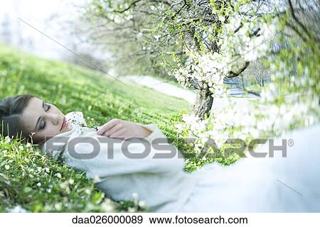 Teenage girl lying on the ground, holding flower, eyes closed View Large Photo Image Stock Photo - Teenage girl lying on the ground, holding flower, eyes closed. Fotosearch