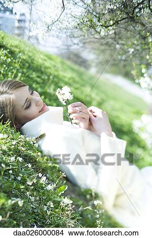 Teenage girl lying on the ground with eyes closed, holding flower, smiling, tilted view View Large Photo Image Picture - Teenage girl lying on the ground with eyes closed, holding flower, smiling, tilted view. Fotosearch