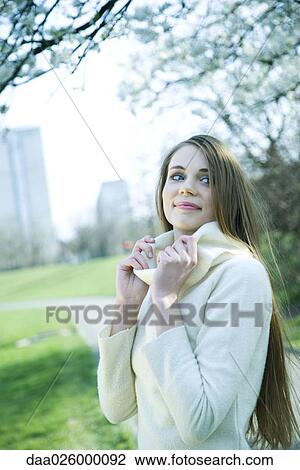 Stock Image - Teenage girl pulling up turtleneck, smiling, looking away. Fotosearch