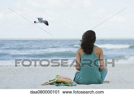Teenage girl sitting on beach looking at ocean, rear view View Large Photo Image Stock Image - Teenage girl sitting on beach looking at ocean, rear view. Fotosearch