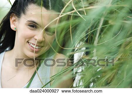 Teenage girl smiling through tall grass at camera View Large Photo Image Stock Photo - Teenage girl smiling through tall grass at camera. Fotosearch