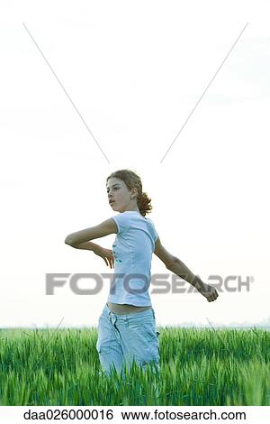 Teenage girl standing in field, doing spinal twist View Large Photo Image Stock Photograph - Teenage girl standing in field, doing spinal twist. Fotosearch