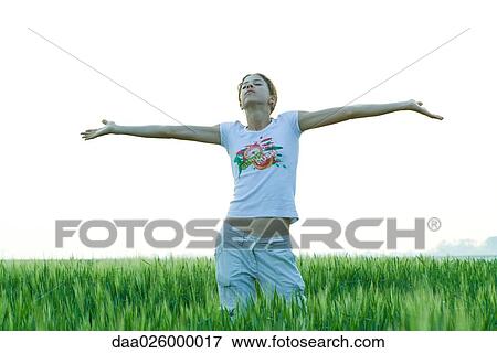 Teenage girl standing in field with arms outstretched, eyes closed View Large Photo Image Stock Photo - Teenage girl standing in field with arms outstretched, eyes closed. Fotosearch