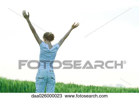 Teenage girl standing with arms raised, rear view View Large Photo Image Stock Image - Teenage girl standing with arms raised, rear view. Fotosearch