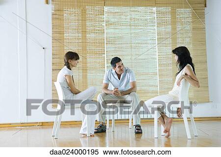 Three adults sitting in chairs, having therapy session, smiling View Large Photo Image Stock Photography - Three adults sitting in chairs, having therapy session, smiling. Fotosearch