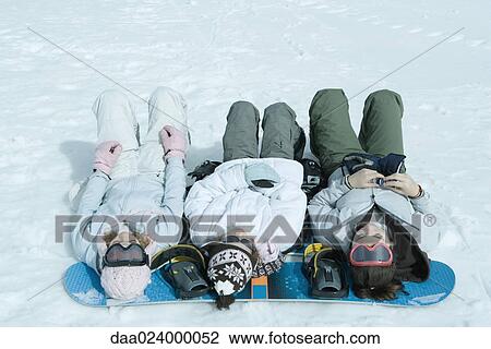 Three sisters lying on snow with heads resting on snowboard View Large Photo Image Stock Image - Three sisters lying on snow with heads resting on snowboard. Fotosearch