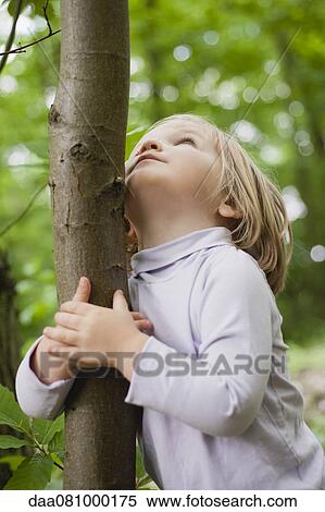 Toddler girl embracing tree trunk, looking up View Large Photo Image Stock Photography - Toddler girl embracing tree trunk, looking up. Fotosearch
