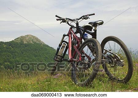 Stock Image - Two bicycles leaning against each other on hilltop. Fotosearch