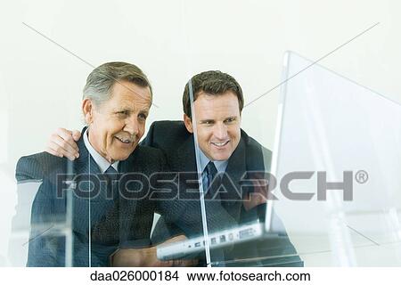 Two businessmen looking at laptop computer together, low angle view View Large Photo Image Picture - Two businessmen looking at laptop computer together, low angle view. Fotosearch