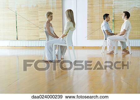 Stock Photo - Two pairs of adults sitting together during therapy session. Fotosearch