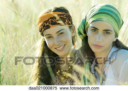 Stock Photography - Two young women sitting in field, portrait. Fotosearch