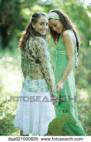 Two young women standing in woods, one looking over shoulder at camera View Large Photo Image Stock Photography - Two young women standing in woods, one looking over shoulder at camera. Fotosearch