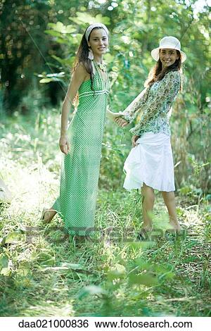 Two young women standing in woods, holding hands View Large Photo Image Stock Photograph - Two young women standing in woods, holding hands. Fotosearch