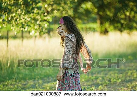 Two young women walking outdoors, holding hands, one peeking at camera View Large Photo Image Stock Photo - Two young women walking outdoors, holding hands, one peeking at camera. Fotosearch