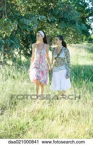 Stock Image - Two young women walking through field. Fotosearch