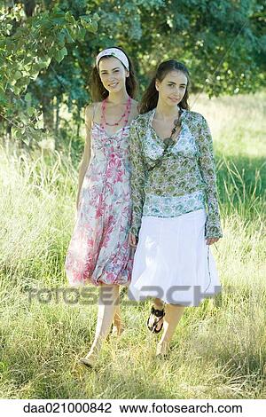 Stock Image - Two young women walking through field. Fotosearch