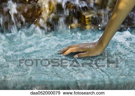 Stock Photo - Water flowing from waterfall over woman's hand. Fotosearch