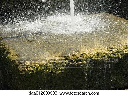 Stock Image - Water pouring onto stone block. Fotosearch