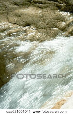 Stock Image - Water running over rock, close-up. Fotosearch