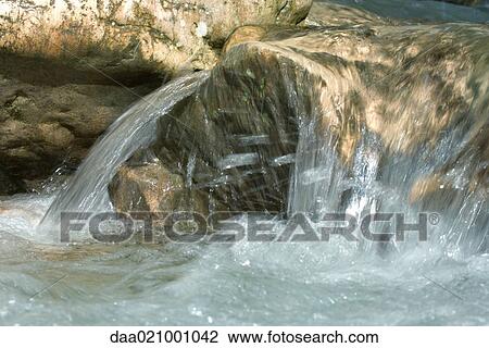 Stock Image - Water running over rock, close-up. Fotosearch
