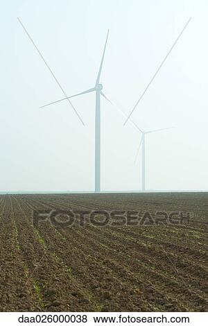 Wind turbines in cultivated field View Large Photo Image Stock Photo - Wind turbines in cultivated field. Fotosearch
