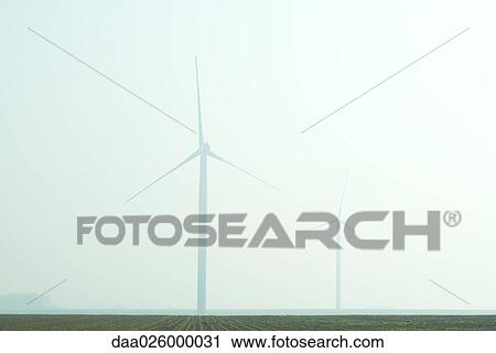 Stock Image - Wind turbines in foggy landscape. Fotosearch