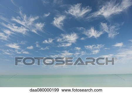 Wispy clouds over tranquil sea View Large Photo Image Stock Photo - Wispy clouds over tranquil sea. Fotosearch