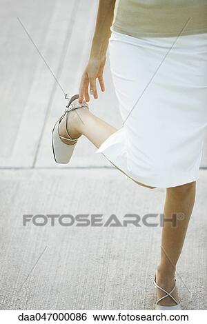 Woman adjusting strap on high heel shoes, low section View Large Photo Image Stock Photograph - Woman adjusting strap on high heel shoes, low section. Fotosearch