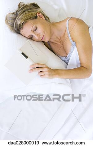 Woman asleep in bed with open book next to her View Large Photo Image Stock Photo - Woman asleep in bed with open book next to her. Fotosearch