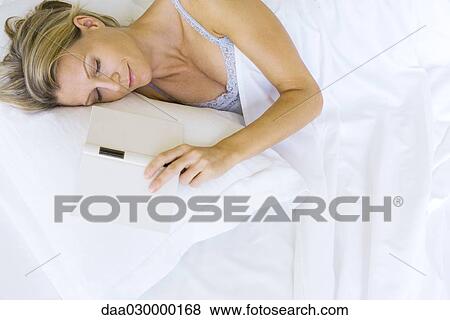 Stock Photo - Woman asleep in bed with open book next to her. Fotosearch