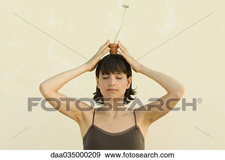 Woman balancing small potted plant on her head View Large Photo Image Stock Photo - Woman balancing small potted plant on her head. Fotosearch