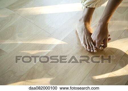 Stock Image - Woman bending forward touching big toe, low section, cropped. Fotosearch