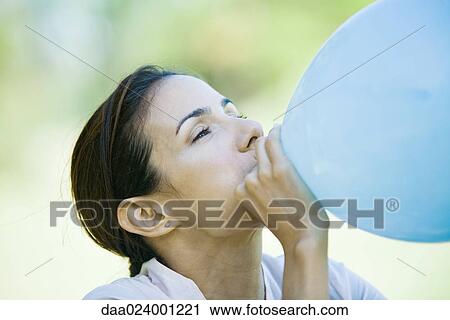 Stock Image - Woman blowing up balloon, cropped. Fotosearch
