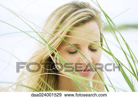 Woman closing eyes, seen through grass, close-up View Large Photo Image Stock Photo - Woman closing eyes, seen through grass, close-up. Fotosearch