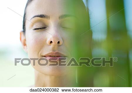 Woman closing eyes, smiling, bamboo in blurred foreground View Large Photo Image Stock Image - Woman closing eyes, smiling, bamboo in blurred foreground. Fotosearch