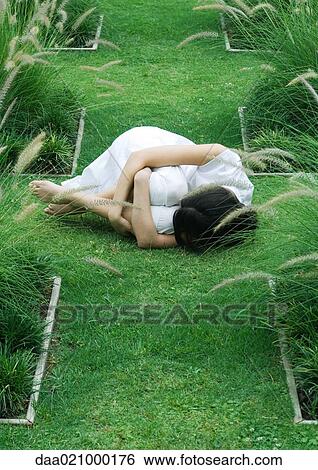 Woman curled up in fetal position on grass View Large Photo Image Stock Photograph - Woman curled up in fetal position on grass. Fotosearch