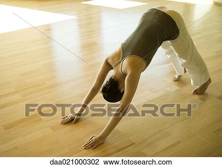 Stock Image - Woman doing downward dog pose. Fotosearch