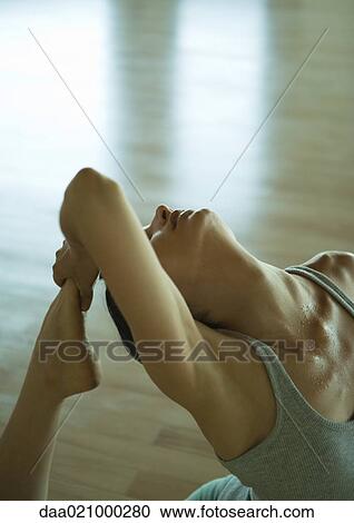 Stock Image - Woman doing one-legged king pigeon pose, partial high angle view. Fotosearch