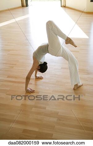 Stock Photo - Woman doing one-legged wheel pose. Fotosearch