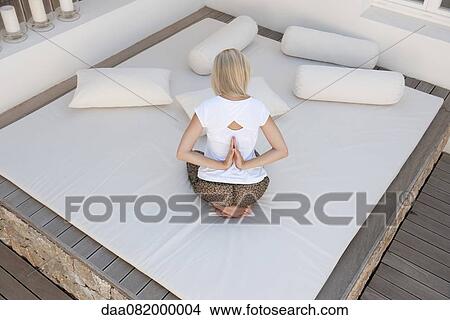 Woman doing reverse prayer pose on bed in patio, rear view View Large Photo Image Picture - Woman doing reverse prayer pose on bed in patio, rear view. Fotosearch