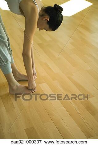 Woman doing standing forward bend, partial view View Large Photo Image Stock Photo - Woman doing standing forward bend, partial view. Fotosearch