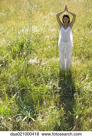 Stock Photo - Woman doing yoga pose in field. Fotosearch