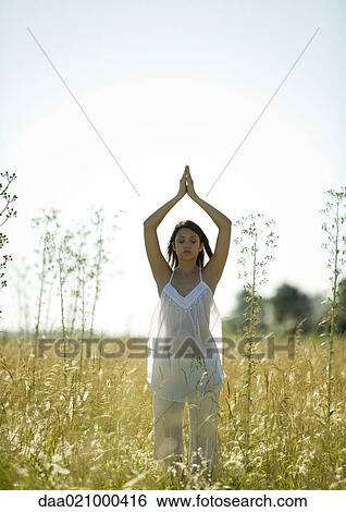 Stock Photograph - Woman doing yoga pose in field. Fotosearch